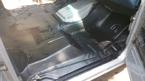 1996 Ford Bronco - The interior floor pan of a vehicle has been treated with black sound deadening material.