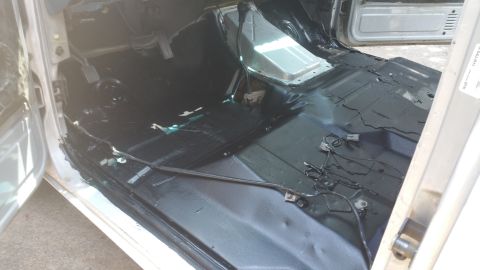1996 Ford Bronco - The interior floor of a vehicle is shown after the carpet has been removed, revealing the underlying structure and wiring.