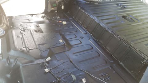 1996 Ford Bronco - The interior floor of a vehicle shows exposed wiring and a black protective coating.