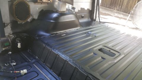1996 Ford Bronco - The interior floor of a vehicle, coated in black, shows a ribbed metal surface and some wiring.