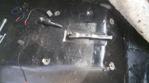 1996 Ford Bronco - Tools and wiring are scattered on the black floor of a vehicle's interior.