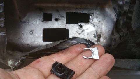 1996 Ford Bronco - A close-up shows a hand holding a small metal clip and a black fastener, with a background of metal brackets.