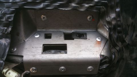 1996 Ford Bronco - Close-up view of a metal bracket with various openings and fasteners, likely part of a vehicle's interior.