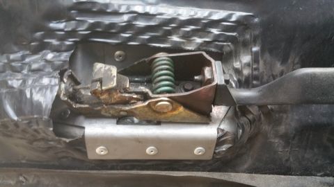 1996 Ford Bronco - Close-up view of a vehicle's interior door latch mechanism, showing the internal components and a green spring.