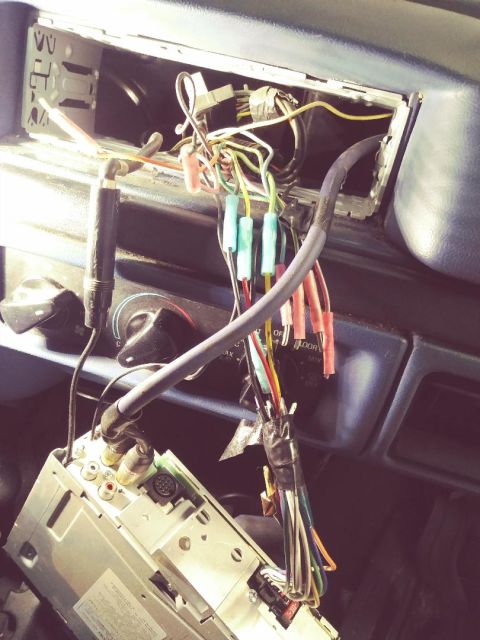 1996 Ford Bronco - Vehicle dash with the radio removed, showing a bundle of multicolored wires and RCA connectors during a stereo install.