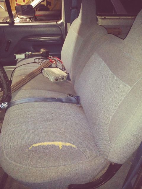 1996 Ford Bronco - The interior of a vehicle shows a damaged seat and various electronic components on the center console.