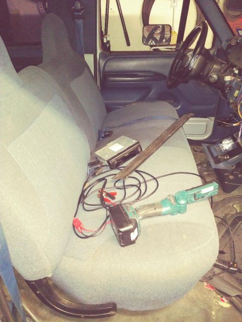 1996 Ford Bronco - The interior of a vehicle shows the passenger seat covered with car stereo components and wiring, alongside the steering wheel and dashboar…