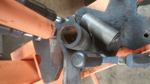 1996 Ford Bronco - A bent metal tube and a metal sleeve are clamped in place, likely for repair or modification of a vehicle's rear suspension.