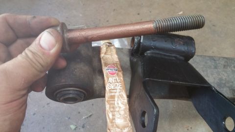 1996 Ford Bronco - A close-up shows a bolt, anti-seize lubricant, and a vehicle suspension part.