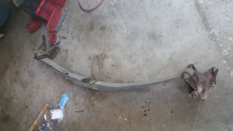 1996 Ford Bronco - A single leaf spring and its mounting bracket are shown lying on a concrete surface.