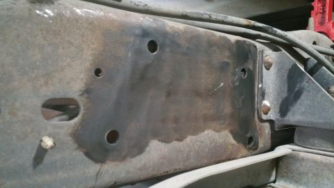 1996 Ford Bronco - Detail of a vehicle's frame rail, showing rust and a bolted bracket, likely part of the rear suspension system.