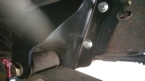 1996 Ford Bronco - Close-up of a black metal suspension bracket bolted to rusty frame components.