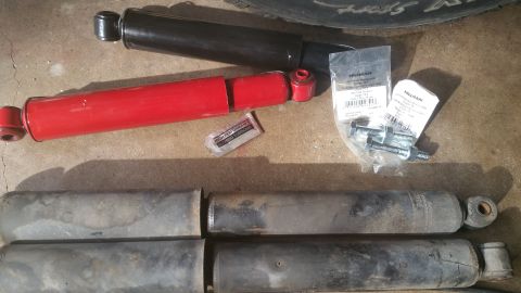 1996 Ford Bronco - New and used shock absorbers laid out with mounting hardware and a packet of lubricant.