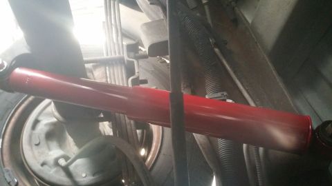 1996 Ford Bronco - Close-up of a red shock absorber on a vehicle's rear suspension system.