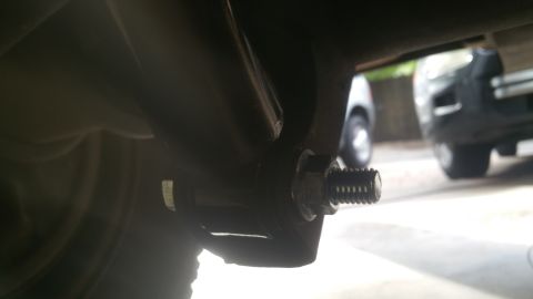 1996 Ford Bronco - Detail of a bolt and bracket on the underside of a vehicle, with other vehicles visible in the background.