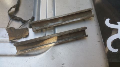 1996 Ford Bronco - Two metal channels and some debris are visible on a textured surface.