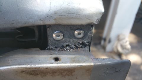 1996 Ford Bronco - A close-up view shows a metal bracket that has been welded and secured with two screws, likely part of a vehicle's bumper mounting system.