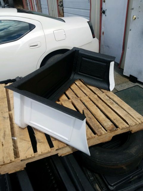 1923 Ford Model T - A white Dodge Charger's rear bumper and quarter panel are displayed on a wooden pallet, with a tire visible below.