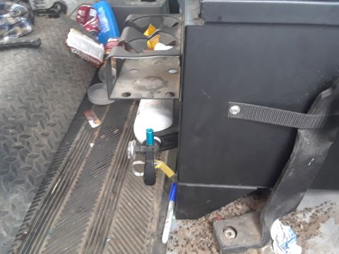 1985 Ford Bronco - The interior of a vehicle shows a fire extinguisher mounted next to a cup holder and scattered debris on the floor.
