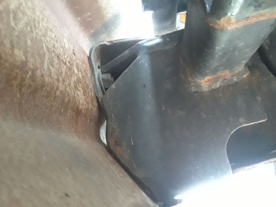 Close-up of a rusty vehicle frame rail and a black metal hitch bracket