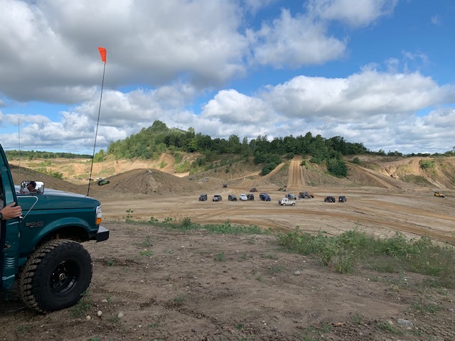 Green 1996 Ford Bronco parked at off-road park with other vehicles in background