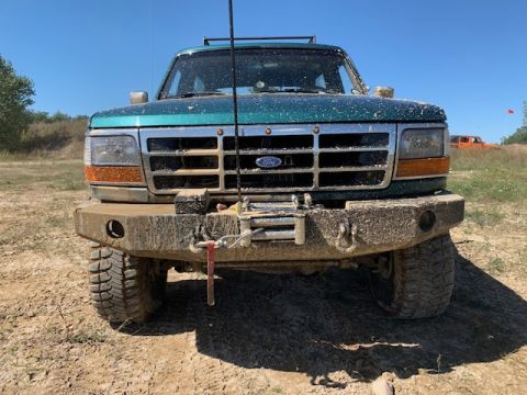 1996 Ford Bronco - Mud-covered 1996 Ford Bronco front end with a winch and custom bumper.
