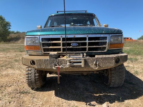 1996 Ford Bronco - This Ford truck, likely from the mid-1990s, is covered in mud and equipped with an off-road winch.