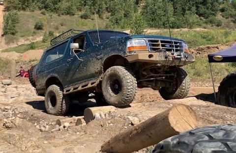 1996 Ford Bronco - This modified Ford Bronco navigates a challenging obstacle on a dirt trail.