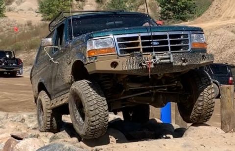 1996 Ford Bronco - This 1996 Ford Bronco is shown off-roading on a challenging course with mud splattered on its body.