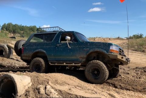 1996 Ford Bronco - This 1996 Ford Bronco is navigating a challenging off-road course with muddy terrain.