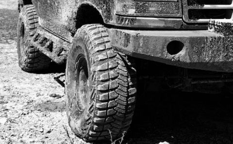 1996 Ford Bronco - The front wheel and bumper of a dirty off-road vehicle are shown in this close-up shot.
