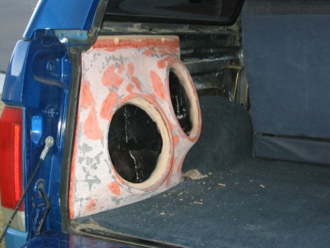 1989 Ford Bronco - Custom subwoofer enclosure being installed in the rear cargo area of a blue vehicle.