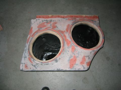 1989 Ford Bronco - This unfinished custom subwoofer enclosure has two large openings for speakers and appears to be made of wood and filler material.
