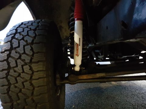 1978 Ford Bronco - A close-up, low-angle view of the suspension and tire of a vehicle, likely an off-road vehicle, showing a Rancho RS5000 shock absorber and…