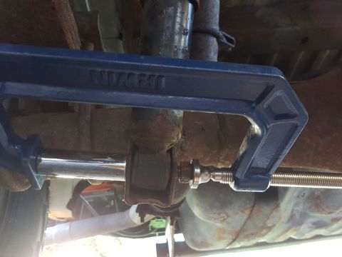 1978 Ford Bronco - A blue Irwin C-clamp is used to compress a shock absorber bushing on the underside of a vehicle. The vehicle appears to be a 1978 Ford Bron…