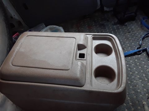 1994 Ford Bronco - A tan plastic center console with dual cup holders and a hinged lid is shown in a vehicle's interior. The console appears to be a storage c…