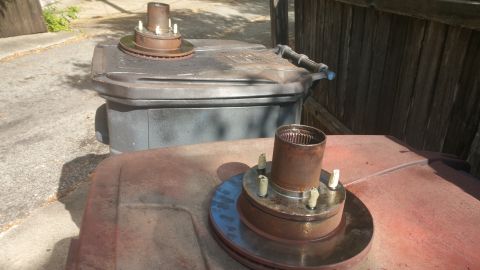 1996 Ford Bronco - Two rusty wheel hubs with brake rotors are placed on top of a dark gray trash can and a red surface. The wheel hubs have five studs each an…