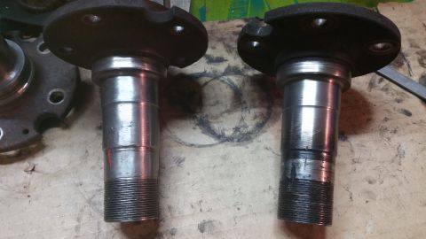 1996 Ford Bronco - Two metal wheel hubs with threaded ends and bolt holes are shown side-by-side on a workbench.
