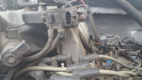1996 Ford Bronco - The image shows a close-up view of a vehicle's engine bay, focusing on the distributor cap, spark plug wires, and a sensor attached to the…