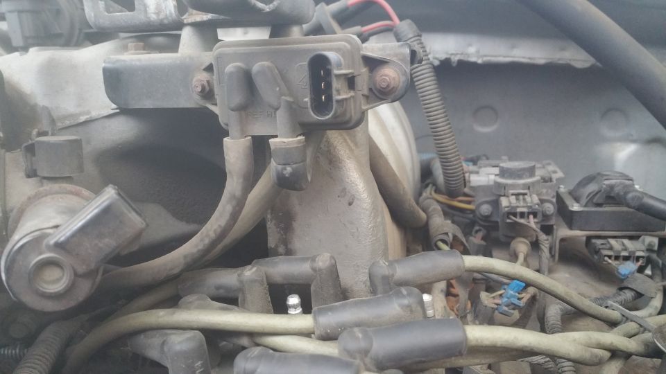 Close-up of a vehicle engine bay showing distributor cap, spark plug wires, and sensor.