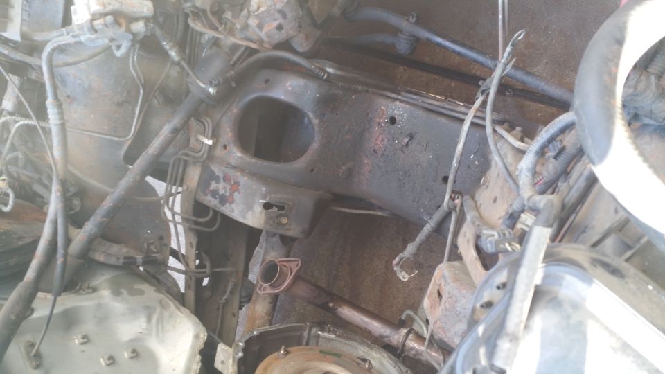 1996 Ford Bronco engine bay with hoses, wiring, and rust.