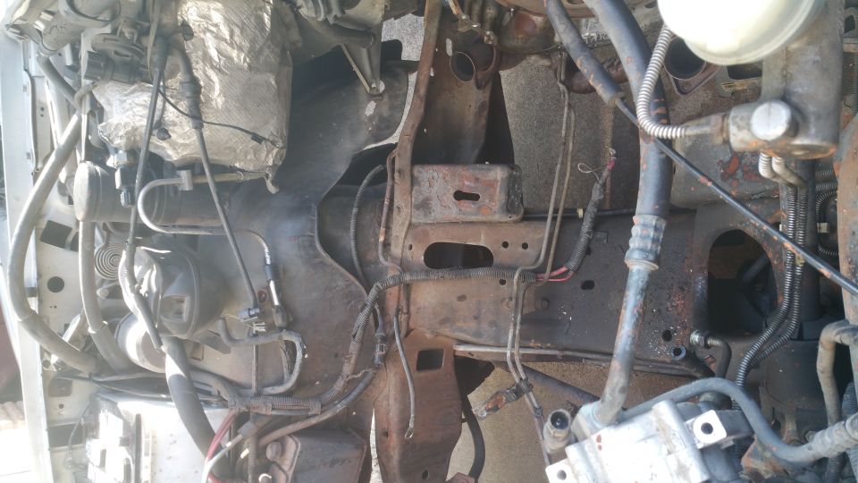 1996 Ford Bronco engine bay with rusted frame and visible engine parts.