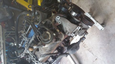 1996 Ford Bronco - A disassembled engine is shown, possibly from a 1996 Ford Bronco, with various components including pulleys, hoses, and a chain. The engine…