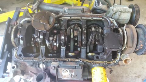 1996 Ford Bronco - A disassembled V8 engine is shown, with the crankshaft, connecting rods, and oil pan visible. The engine appears to be in a workshop or gar…