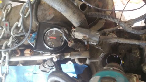 1996 Ford Bronco - A close-up view of an engine bay shows a black-faced gauge with a red needle pointing to approximately 25, mounted among various hoses, wir…