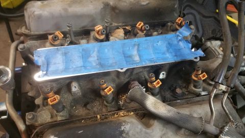 1996 Ford Bronco - A close-up view of a V8 engine's intake manifold with fuel injectors installed. Blue painter's tape covers a portion of the manifold.