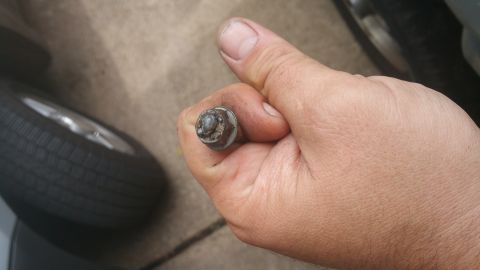 1996 Ford Bronco - A close-up shot shows a hand holding a lug nut with a tire and wheel in the background. The lug nut appears to be made of metal and shows s…
