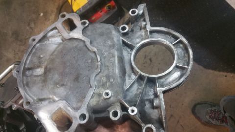 1996 Ford Bronco - This is a close-up shot of a metal engine part, likely a timing cover or water pump housing, showing casting marks and some wear. The part…