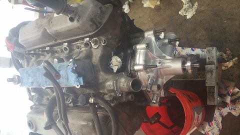 1996 Ford Bronco - A close-up view of a Ford engine, possibly during a repair or rebuild, with a new silver water pump installed on the driver's side. Various…