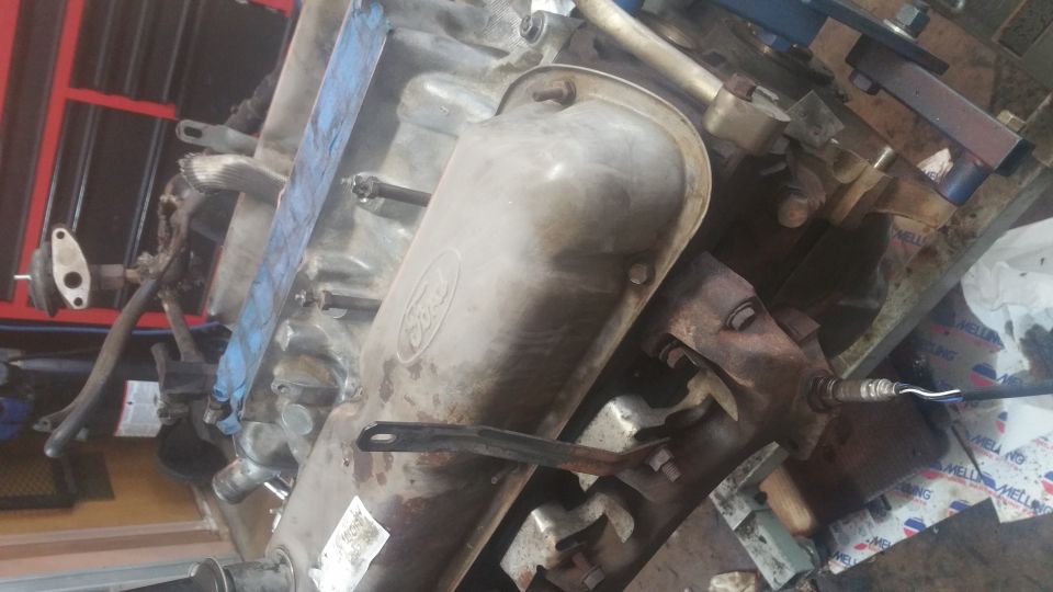 Ford V8 engine block with valve cover removed, exhaust manifold, and oxygen sensor.